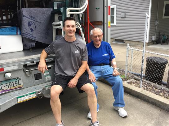 Two men relax on a truck tailgate, enjoying a break during a moving day.