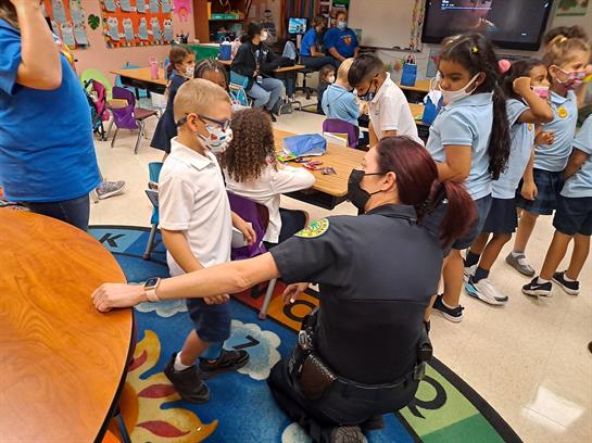 Kids engage with a police officer, learning safety in a lively classroom setting.