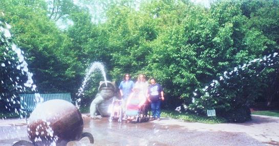 Family is gathered around a whimsical fountain in the park while enjoying a sunny day outdoors.