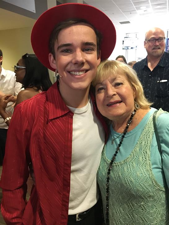 Two people enjoy a joyful moment at a lively event amid a cheerful crowd.