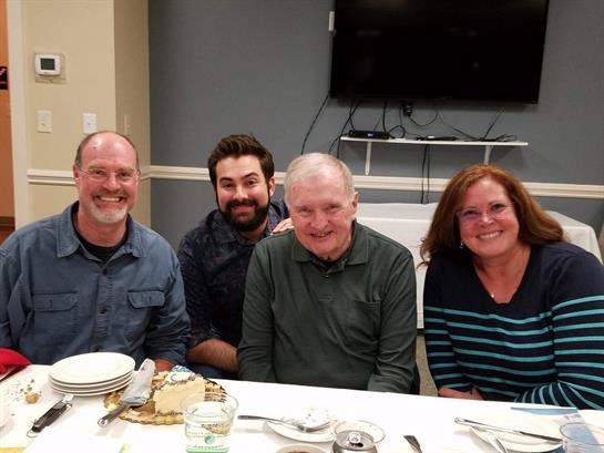 Four people enjoy a meal together at a dining table, sharing laughter and good food.