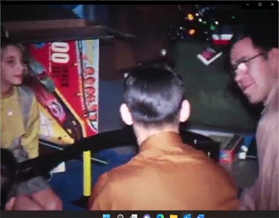 Friends gather around a vintage arcade game, sharing laughter and excitement during the day.