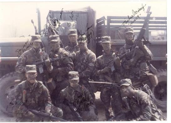 Soldiers gather together, proudly displaying their uniforms and weapons at a military base.