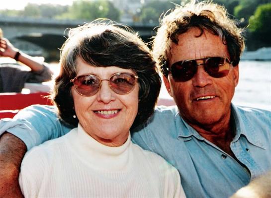 A happy couple in sunglasses enjoys a warm day by the water.
