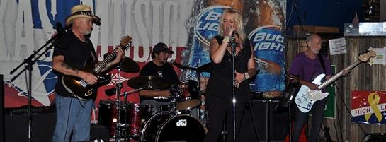Band members play instruments while a female vocalist captivates the audience during a lively show.