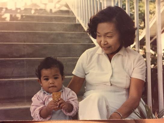 Warm afternoon light highlights an elderly woman and a child enjoying ice cream together on steps.