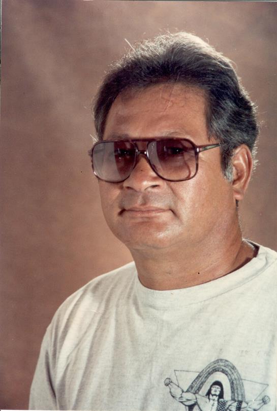 A man wearing sunglasses stands with a serious expression, giving a strong presence in the image.