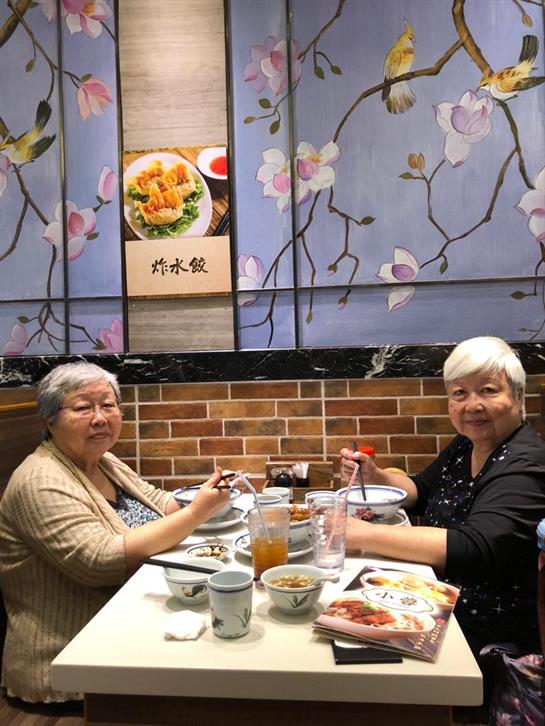 Two senior women share a meal and enjoy each other's company at a lovely table.