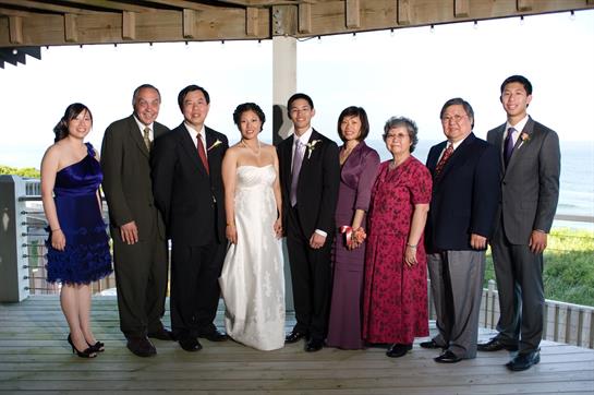 Group of family members dressed elegantly for a wedding, sharing joyful moments on a terrace.