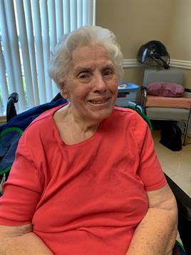 A joyful senior woman enjoys her time in a care center, engaging with staff and residents.
