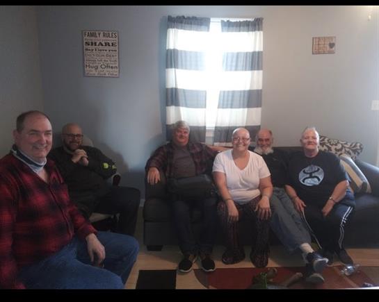 Friends are seated comfortably in a bright living room, sharing laughter and conversation.