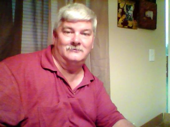 Older gentleman enjoys a relaxed moment at home, smiling while seated at a table.