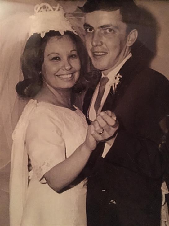 A joyful newlywed couple dances together at their wedding reception, surrounded by soft lighting.