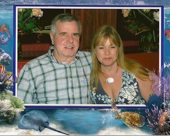 A couple sits together, smiling warmly, surrounded by floral decorations and a relaxed atmosphere.