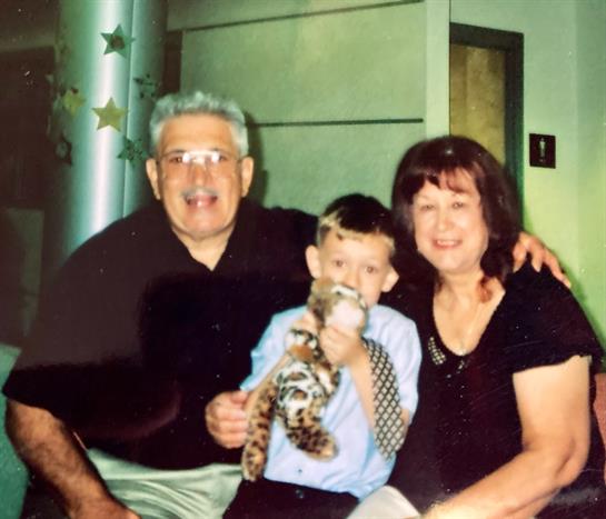 Grandchild shares a cozy moment with grandparents, holding a stuffed animal indoors.