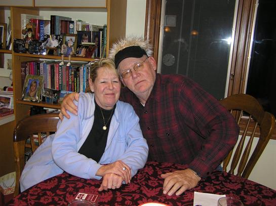A joyful couple sits at a table, embracing and sharing a warm moment in their cozy home.