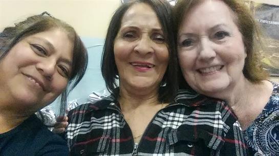 Three women joyfully pose for a close-up at a friendly gathering, showcasing their connection.