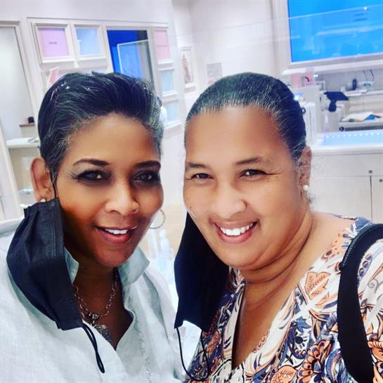 Two friends are happily posing for a friendly picture inside a stylish shop, smiling.