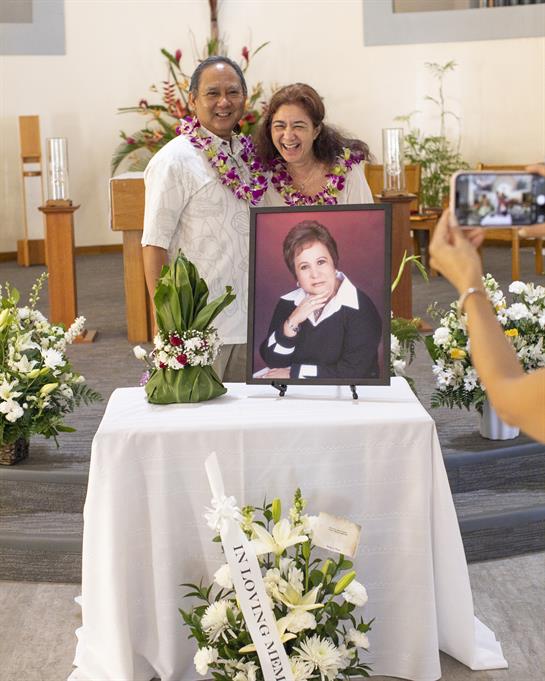 People embrace and take photos together at a memorial service honoring a beloved individual.