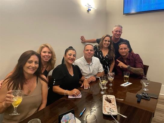 A group of friends smiling and sharing a meal while celebrating a special occasion at a restaurant.