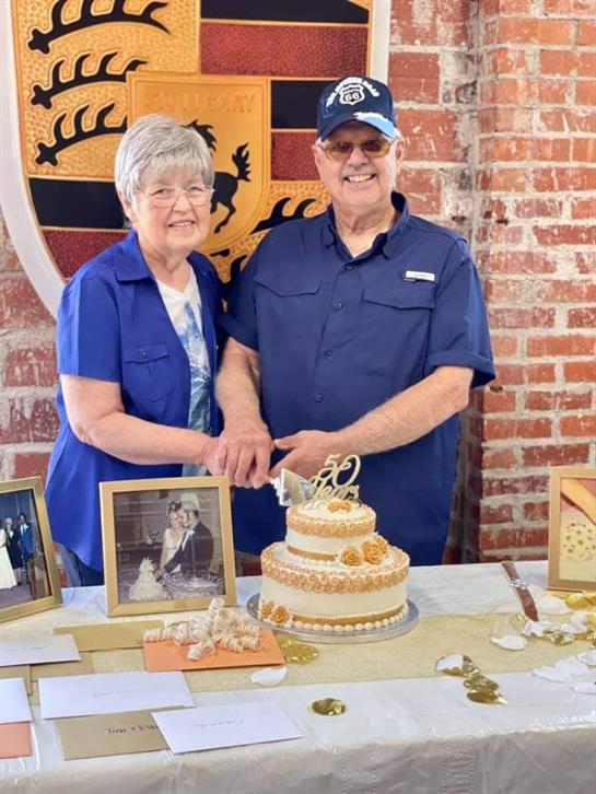 Couple joyfully marks their 50th wedding anniversary surrounded by family, cake, and memories.