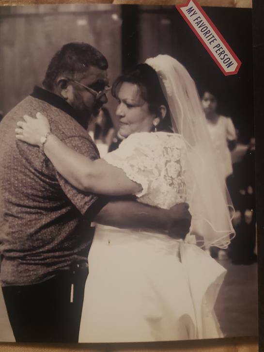 A joyful couple dances intimately at their wedding reception in a sunny outdoor setting.