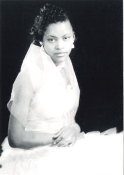 A young woman sits elegantly in formal attire, showcasing her timeless beauty and poise.