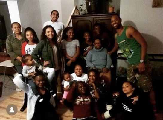 A large group of family members gathers in a cozy living room, sharing joy and laughter.