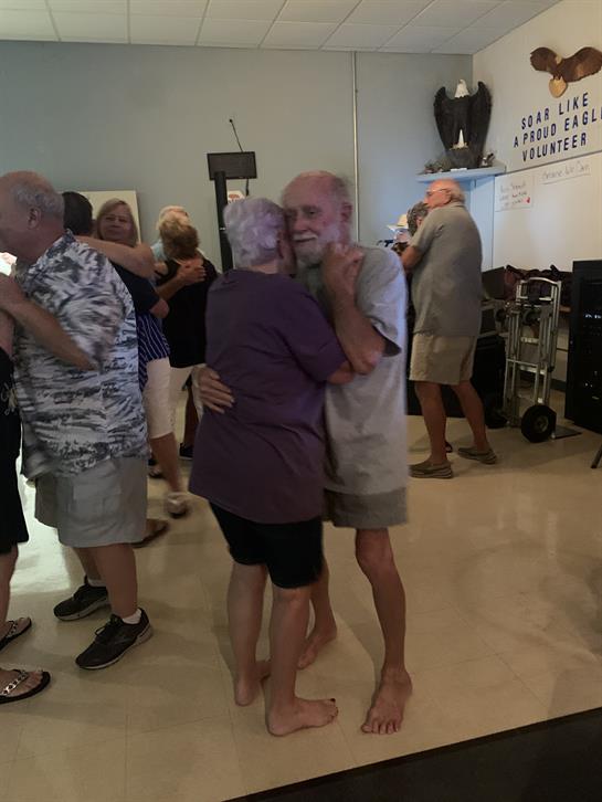 Elderly couples dance joyfully together at a community gathering on a warm afternoon.