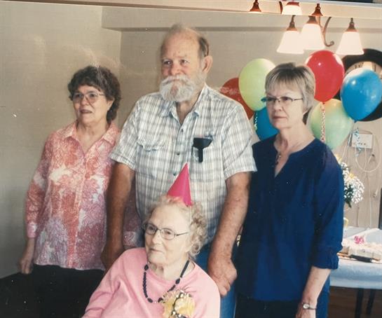 Family celebrates an elderly woman's joyful birthday amid colorful decorations.