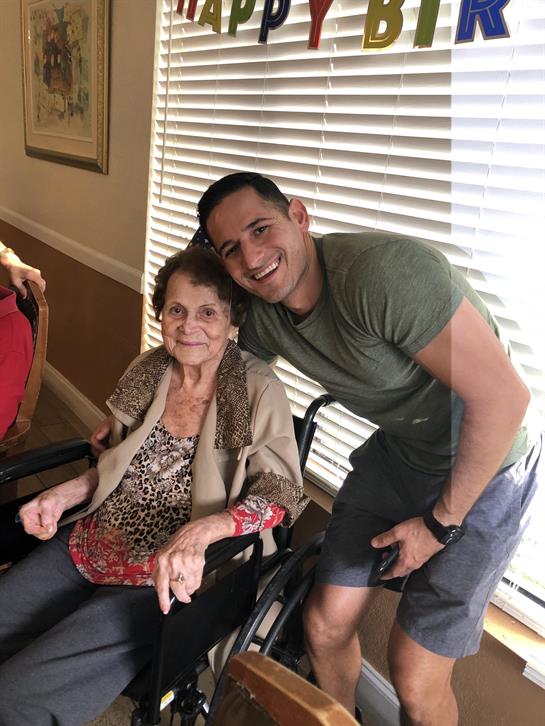 A young man shares a joyful moment with an elderly woman in a care facility.