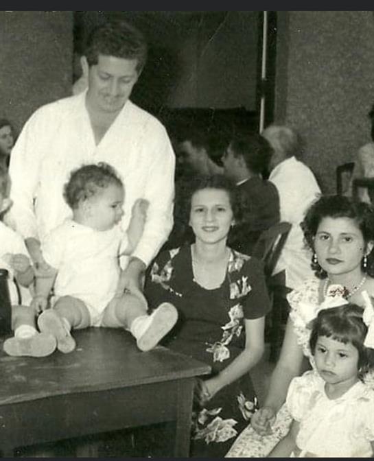 Several adults and children interact at a lively gathering, showcasing family bonds and joy.