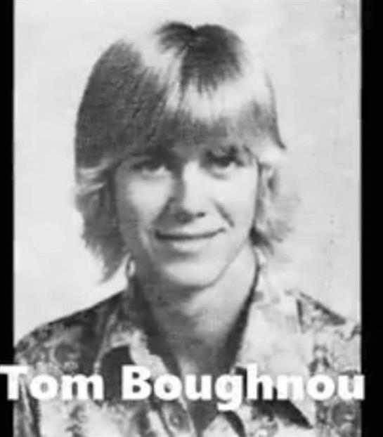 A blonde young man with light hair and a patterned shirt poses for a portrait at school.