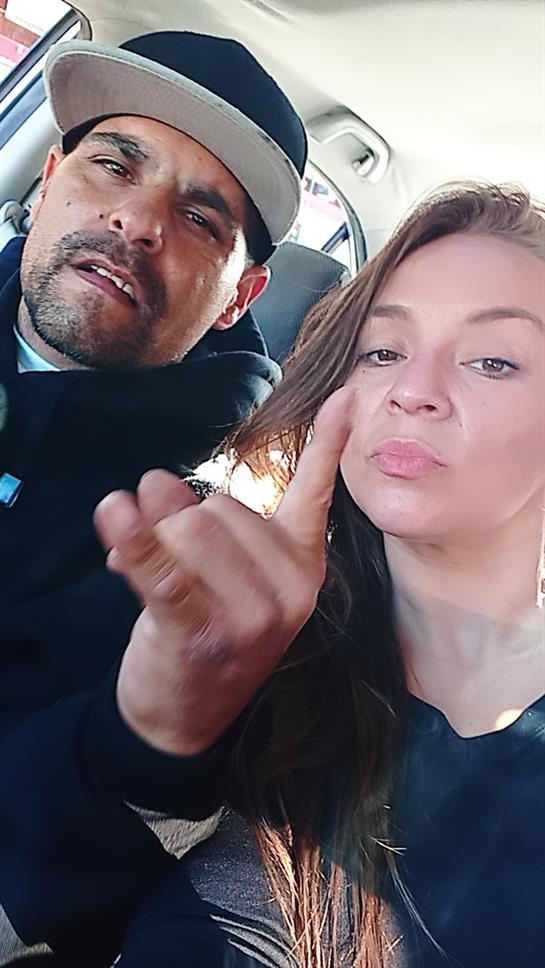 A man and woman are having fun inside a car, displaying cheerful expressions.