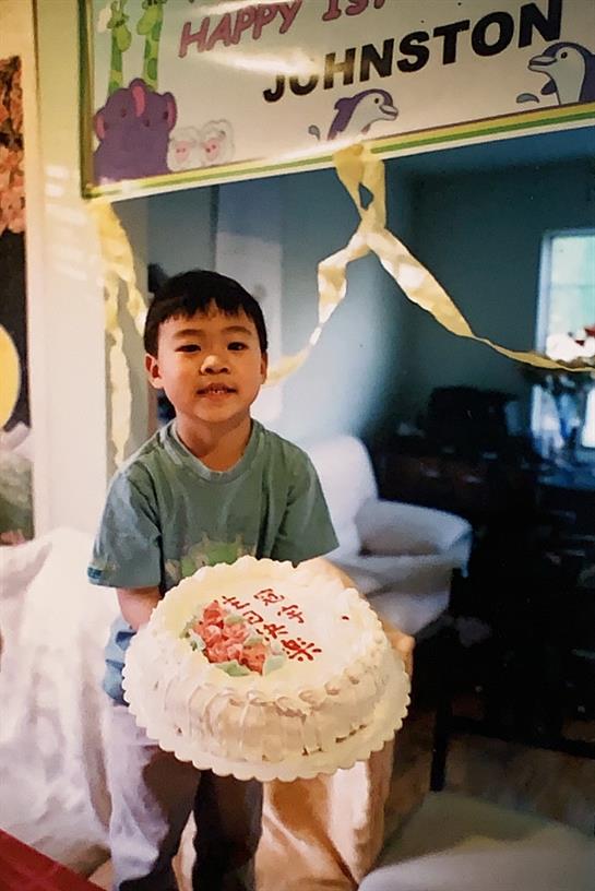 A cheerful young boy is proudly presenting a beautifully decorated cake during a birthday party.