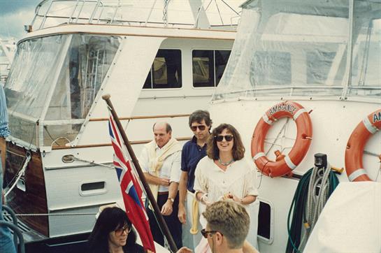 Group of individuals converse and enjoy their time at the marina surrounded by boats.