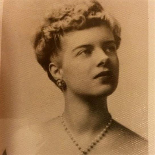 A woman with a refined hairstyle and pearls gazes thoughtfully, dressed in vintage fashion.