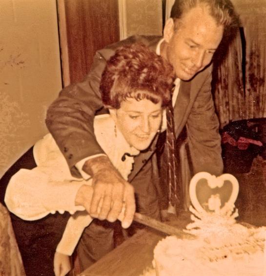 A couple enjoying a heartfelt moment while cutting their wedding cake in a nostalgic setting.