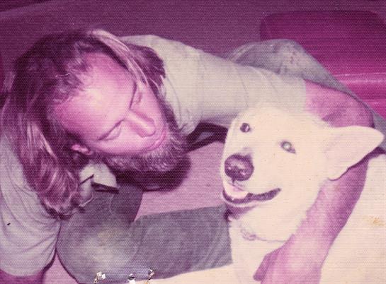A man enjoys quality time with a playful dog, smiling and sharing a joyful moment indoors.