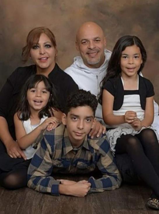 A happy family of five poses closely together, showcasing warmth and joy in a studio environment.