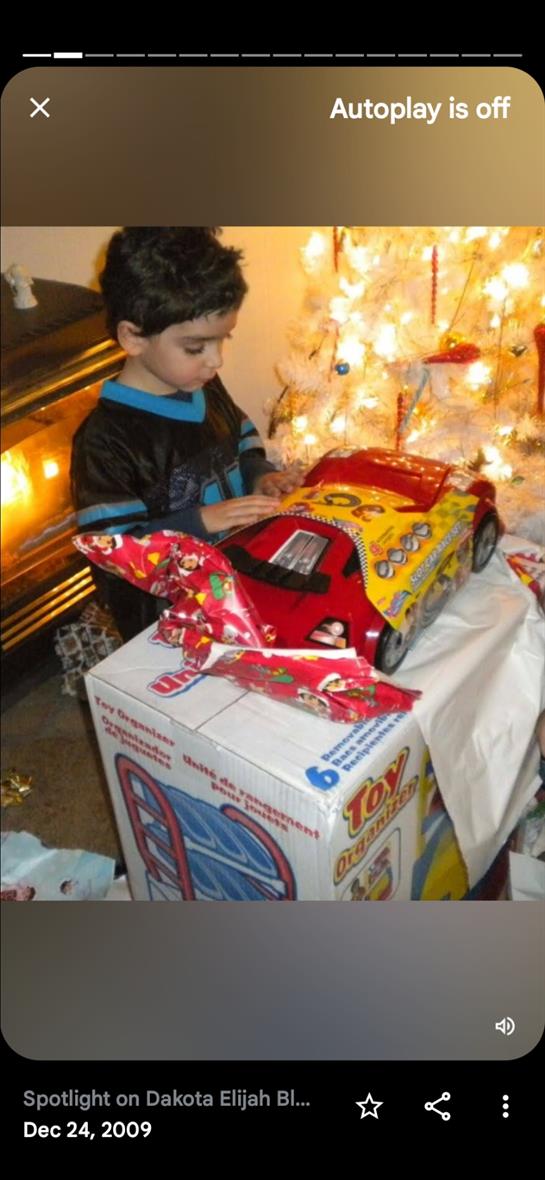A child eagerly opens gifts beneath a glowing holiday tree decorated with lights.