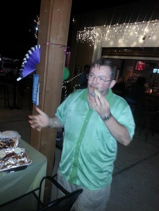 A man in a green shirt relishes his meal at a vibrant outdoor celebration filled with lights.