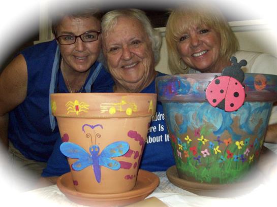 Friends gather to decorate flower pots with vibrant colors and designs while sharing laughter.