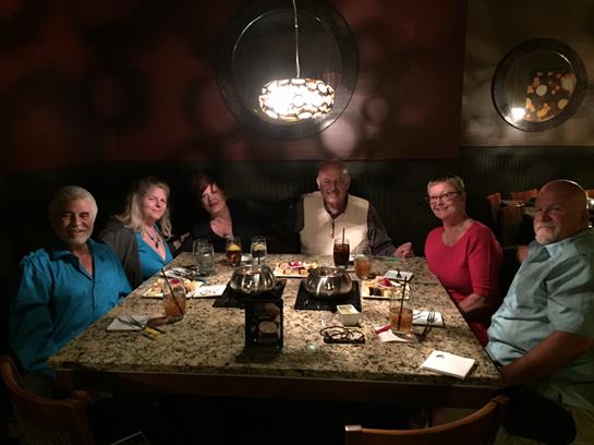 Friends share laughter and conversation while enjoying dinner at a warm, inviting restaurant.