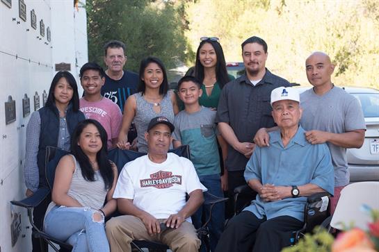 Family members gather for a sunny outdoor event, enjoying each other's company and laughter.