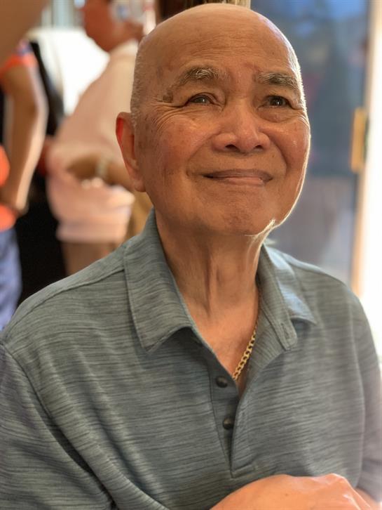 An elderly man enjoys a joyful moment surrounded by friends at a community event indoors.