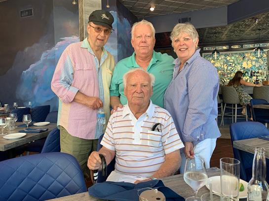 Four friends enjoy a sunny afternoon together at a restaurant.