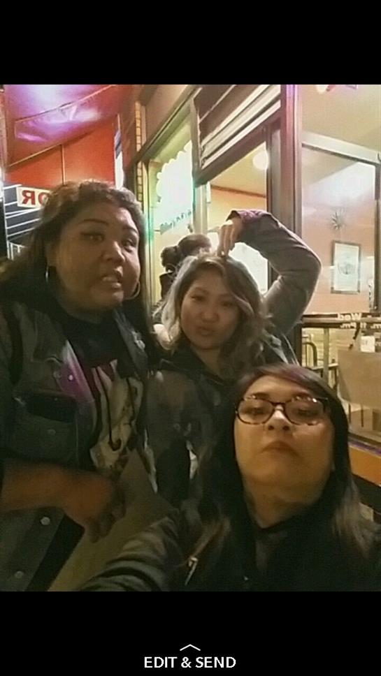 Three friends pose playfully outside a restaurant during a fun evening gathering.
