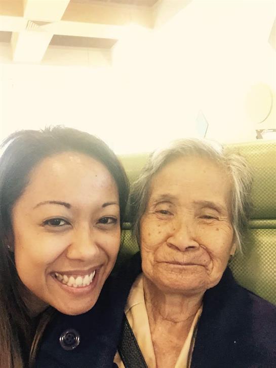 A young woman is smiling brightly next to an elderly woman in a warm and inviting atmosphere.