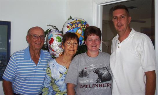 Family members gather to celebrate a birthday, smiling in a cheerful atmosphere with decorations.